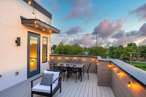 Um deck externo com área de estar, luzes de corda e vista do céu.