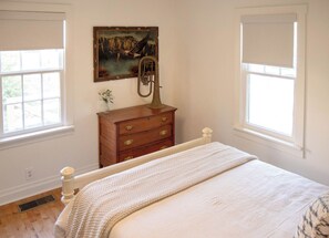 A bedroom with a bed, a dresser, a painting, and a window. - Leipers Fork Bungalow | Hot Tub & Firepit (Franklin)