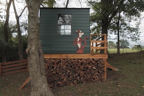 A small cabin with a cartoon tiger mural, a window, and a wooden deck. - Leipers Fork Bungalow | Hot Tub & Firepit (Franklin)