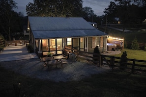 Une cabane rustique avec un toit en métal, une terrasse en bois et un espace extérieur clôturé.
