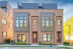 A two-story residential building with a brick facade, large windows, and a flat roof. - Rooftop, Grill, Garage, Near Broadway (Nashville)