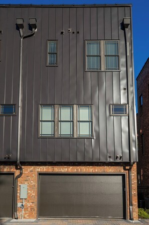 A modern building with a garage door, multiple windows, and a brick base. - Rooftop, Grill, Garage, Near Broadway (Nashville)