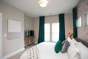 Een hotelkamer met een bed, een televisie op een houten standaard en een raam met gordijnen.