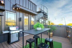 An outdoor patio with a grill, a table, and two stools. - Rooftop, Grill, Garage, Near Broadway (Nashville)