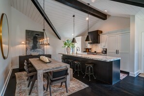 A modern kitchen with a marble island, pendant lighting, and dark wood cabinetry. - Luxury Franklin Farmhouse (Franklin)