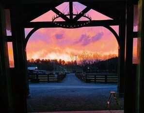A stable with a view of a sunset through an arched opening. - Luxury Franklin Farmhouse (Franklin)