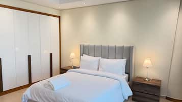 A modern bedroom with a large bed, two bedside tables with lamps, a wardrobe, and a ceiling light.