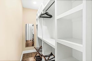A hallway with white shelving units, a wooden chair, and a hanging coat rack. - Printer's Alley Vibes Rooftop Fire Table + Karaoke (Nashville)