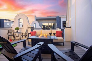 An outdoor patio with a fire feature, seating, and a view of the building's architecture. - Printer's Alley Vibes Rooftop Fire Table + Karaoke (Nashville)