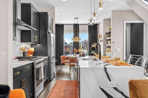 Una cocina moderna con una isla central, electrodomésticos de acero inoxidable y vistas al exterior.