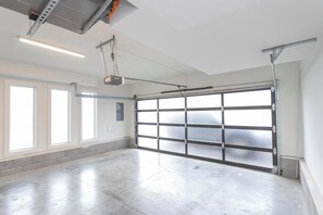 Een garage met een grote, open deur, een aan het plafond gemonteerde projector en een betonnen vloer.