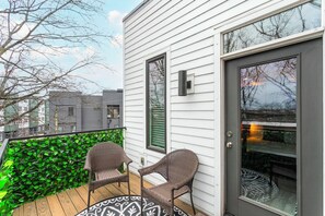 A balcony with two wicker chairs, a patterned rug, and a green leafy wall. - The Grand Ole Opry Live! (Nashville)