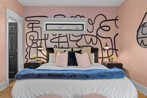 A bedroom with a bed, two bedside tables, a wall-mounted TV, and abstract wall art. - Historic East Nash | 5 Kings, 5 Baths, Walkable (Nashville)