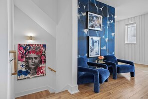 A modern living room with a staircase, blue velvet armchairs, and a large abstract painting on the wall. - Minutes to Downtown | Rooftop Skyline Views (Nashville)