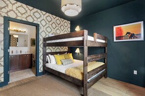Un lit superposé avec une structure en bois, un miroir et une lampe fixée au mur.