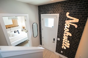 A room with a bed, a mirror, a door, and a wall with a 'Karussell' sign. - Near Downtown | Rooftop | Games (Nashville)