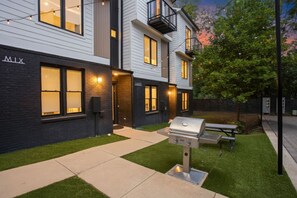 A modern building with a well-maintained lawn and a barbecue grill in the front yard. - 12 South | 7 Beds | 2mi to Broadway (Nashville)