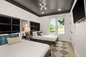 Een slaapkamer met twee bedden, een plafondventilator, een raam en een deur.