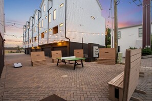 A courtyard with a ping pong table, benches, and a brick floor. - 12 South | 7 Beds | 2mi to Broadway (Nashville)