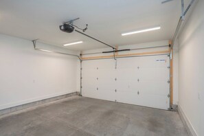 A garage with a white door, fluorescent lighting, and a ceiling-mounted projector. - Rooftop City Views, Garage, Near Broadway (Nashville)