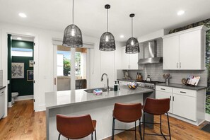 Een moderne keuken met een centraal eiland, hangende verlichting en witte kasten.