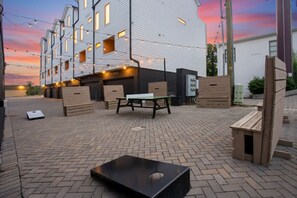 A courtyard with a white building, outdoor furniture, and string lights. - Central to 12 South, Gulch, Broadway | 4.5 Baths (Nashville)
