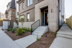 A residential building with a brick facade, a small front yard with a tree, and a staircase leading to the entrance. - 1 Mile to Downtown 4BR w/Rooftop (Nashville)