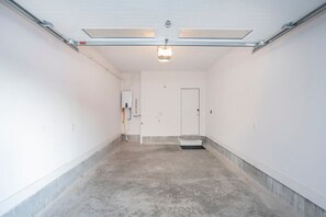 A clean, empty hallway with a white door at the end, a light fixture on the ceiling, and a small step leading to the door. - 1 Mile to Downtown 4BR w/Rooftop (Nashville)