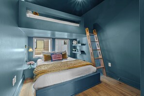 Un dormitorio con una litera, una escalera, una ventana y un estante con adornos.