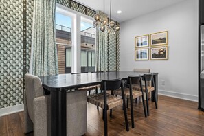 A modern dining area with a long table, chairs, and a chandelier. - 2 Homes | 24 Guests | Rooftop Hot Tub Fire Pit (Nashville)