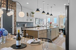 Cozinha moderna com ilha central, iluminação pendente e espaço de refeições preparado para uma refeição.