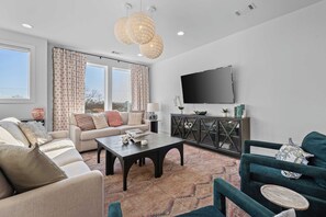 Una sala de estar moderna con un sofá, una mesa de centro y sillones, un televisor de pantalla plana y un aparador decorativo.