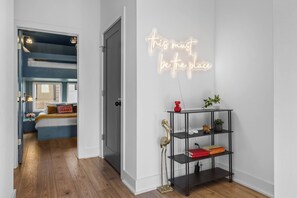 A modern room with a neon sign, a bookshelf, and a bed with a view. - 2 Homes | 24 Guests | Rooftop Hot Tub Fire Pit (Nashville)