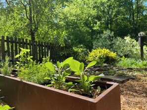 A garden with raised beds, a wooden fence, and a variety of plants. - The Frontier Getaway (Nashville)