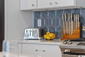 Une cuisine équipée d’un grille-pain, d’un bloc à couteaux et d’un panier de fruits.