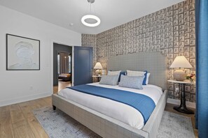 A modern bedroom with a large bed, a decorative wall, and a small table with a lamp. - Nashville Skyline | Rooftop Deck & Fire Pit (Nashville)
