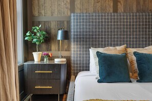 Une chambre à coucher moderne avec un lit, une table de chevet, une lampe et une plante en pot.