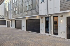 A modern building with grey siding and white trim, featuring garage doors numbered 103C and 103D. - Sleeps 20: Views, HotTub, FirePit, Grill, Parking (Nashville)