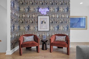 A room with a patterned wallpaper, two velvet armchairs, a small table, and a framed artwork. - Sleeps 20: Views, HotTub, FirePit, Grill, Parking (Nashville)