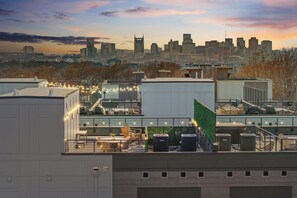 En takterrass med utomhusmöbler, luftkonditioneringsanläggningar och en stadsbild som bakgrund.