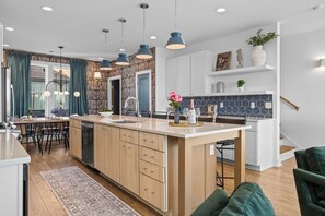 A modern kitchen with a central island, wooden cabinets, and pendant lighting. - Rooftop Hot Tub Views  Parking Mins to Bway (Nashville)