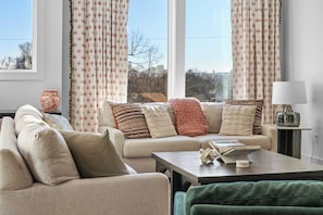A living room with a sofa, a coffee table, and a lamp. - Rooftop Hot Tub Views  Parking Mins to Bway (Nashville)