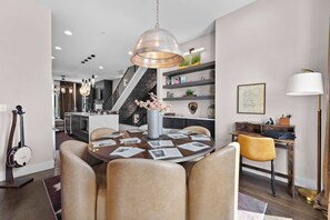 A modern dining area with a round table, chairs, and a hanging light fixture. - The Groovy Songwriter | Gated | Sauna + Peloton (Nashville)