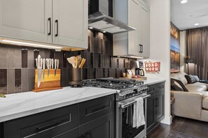 A modern kitchen with a central island, stainless steel appliances, and a decorative sign on the wall. - The Groovy Songwriter | Gated | Sauna + Peloton (Nashville)