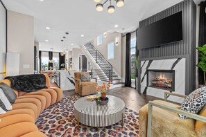 Uma sala de estar moderna com lareira, escada e vista para o exterior.
