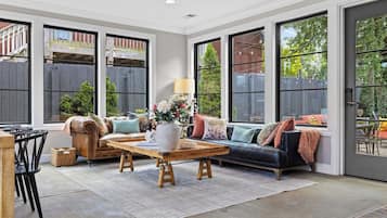 A spacious living room with a leather sofa, a wooden coffee table, and a dining area with chairs.