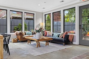 A spacious living room with a leather sofa, a wooden coffee table, and a dining area with chairs.
