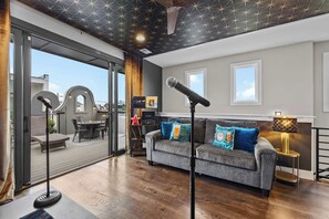 Ein modernes Wohnzimmer mit einem grauen Sofa, einem Stehmikrofon und einem kleinen Tisch mit einer Lampe.