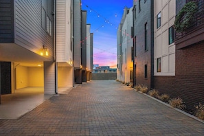 A narrow alleyway with brick paving, flanked by modern buildings with large windows and string lights. - Broadway Honky Tonk Haven w/ Karaoke Stage! (Nashville)
