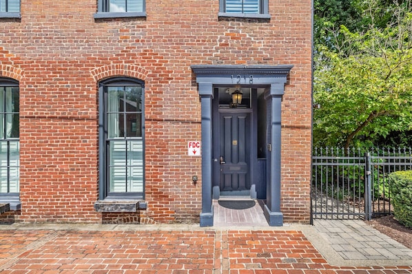 A brick building with a dark blue entrance door, a small window, and a sign indicating a fire department connection. - The Parks Suite | Germantown Inn | Breakfast (Nashville)